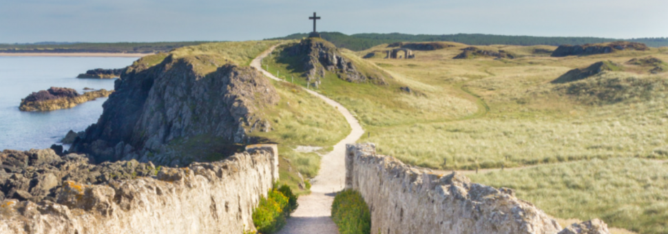 Image of a stone wall -lined path leading to a cross